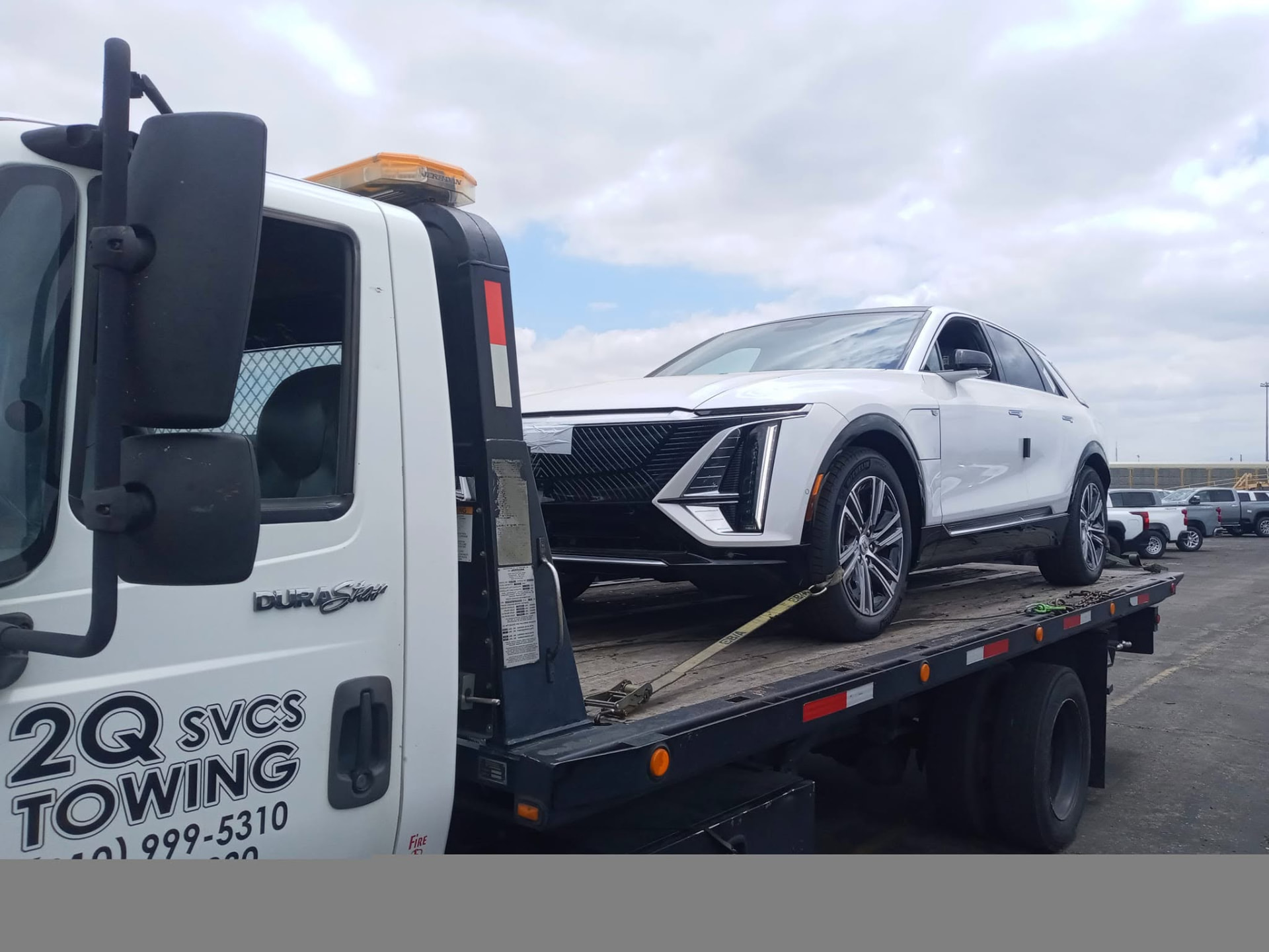 White Cadillac Lyriq secured on a 2Q Svcs & Towing flatbed
