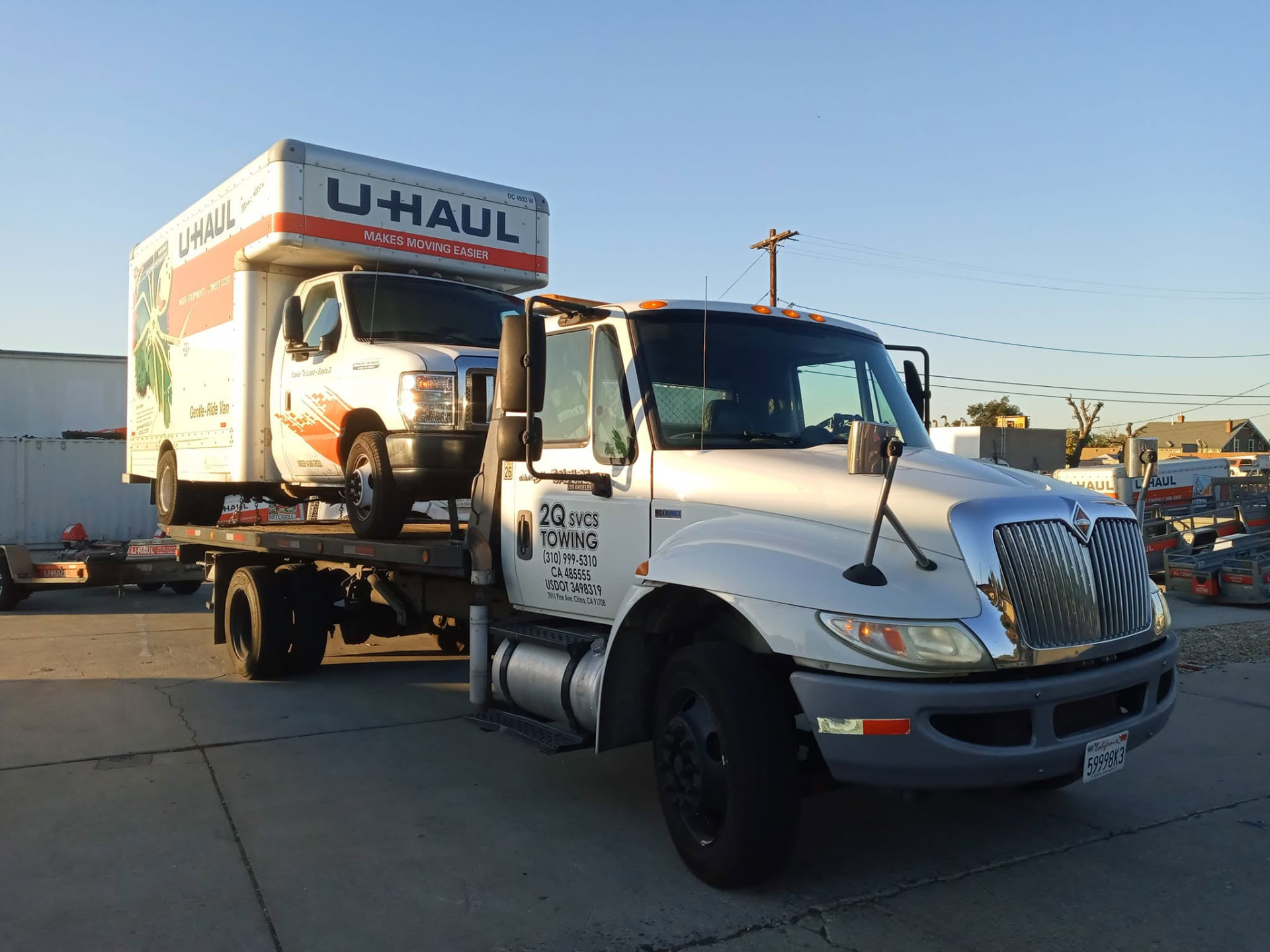 2Q Svcs & Towing truck with a U-Haul box truck at a rental yard